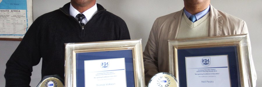 Vlnr is Tommy Volkwyn (hoof) en Neil Pedro (adjunkhoof) van Gansbaai Primêr met hul trofeë en geraamde sertifikate 